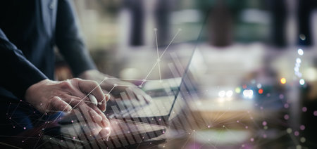 Businessman working online on mobile computer with financial markets in blurred background.