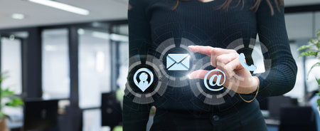 Businesswoman working on virtual computer screen with contact icons on blurred office background.