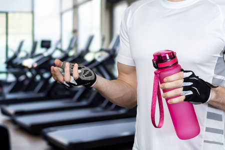 An athlete with a bottle of water stands against a blurred gym background.