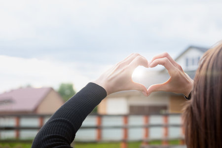 Girl gestures with her hand to show a heart at sunset. The concept of love, compassion and care.の写真素材