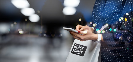 Girl makes a purchase with her phone on Black Friday. Black Friday shopping concept.の写真素材