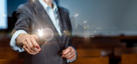 Speaker holding microphone against blurred background of audience.の写真素材
