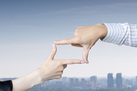 Hands pointing to a crop in front of a city panorama.の写真素材