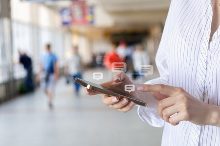 A girl corresponds on a mobile phone against the blurred background of a railway station.の写真素材