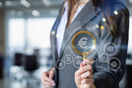 The concept of European market analysis. The manager looks through a magnifying glass at the mechanism for earning euros.の写真素材