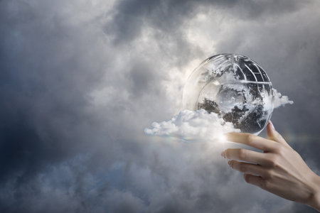 Conceptual support for the peace process in difficult times. Hand supports globe on blurry sky.