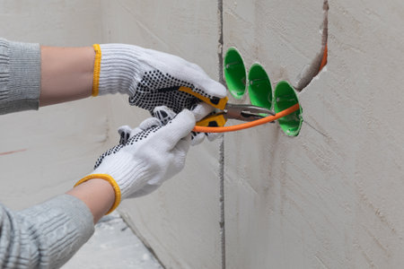 Preparing the electrical cabling. The tradesman uses pliers and a cutting knife to prepare the wiring.の写真素材