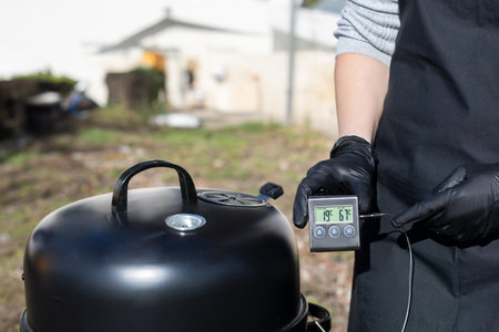 The grill master performs the temperature control. The process of cooking meat in a smokehouse or grill.の写真素材