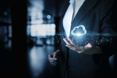 A professional woman in formal attire interacts with a holographic cloud above her hand. The futuristic environment hints at a tech savvy workspace emphasizing modern advancements.の写真素材