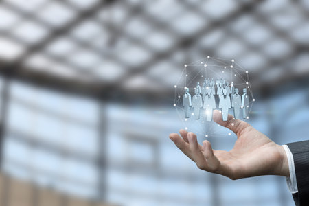 A person extends their hand, displaying a digital network of professional figures. The setting showcases a modern, tech-driven environment, indicating innovation and connectivity.の写真素材