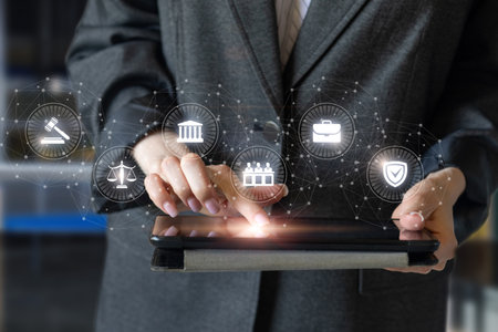 A business professional in a suit interacts with a tablet while surrounded by digital icons representing various tasks, demonstrating modern technology in a professional setting.の写真素材