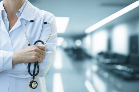 A medical professional stands confidently in a clinic, holding a stethoscope and wearing a white coat. The background features blurred seating, suggesting a healthcare environment.の写真素材