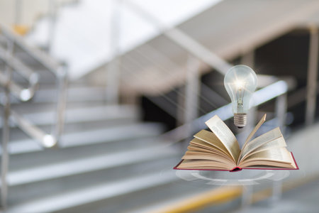 Open book with pages turning sparks a lightbulb above it. This symbolizes the birth of ideas through the pursuit of knowledge in a creative environment, inviting inspiration and innovation.の写真素材