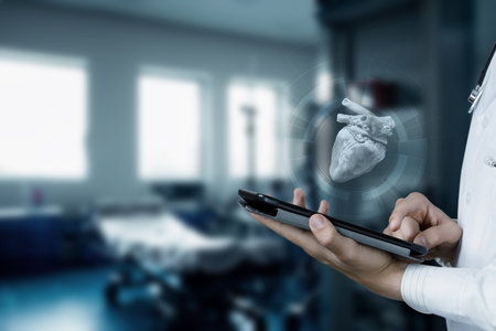 A researcher is utilizing modern technology to study the heart. The focus is on a 3D heart model displayed above a tablet in a contemporary medical setting, enhancing understanding and diagnostics.の写真素材