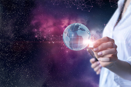 A person holds a glowing globe representing global connectivity and security against a vibrant cosmic background. The imagery emphasizes the intersection of technology and safety.の写真素材