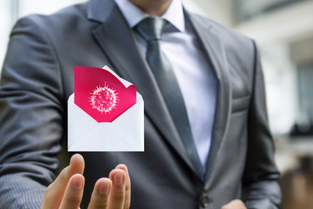 A businessman holds an envelope with a virus symbol, symbolizing the dangers of email viruses. The setting suggests a modern office while highlighting cybersecurity issues.の写真素材