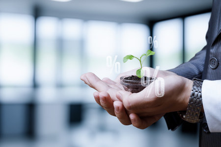 A person holds a small pot with a growing plant in one hand while financial symbols, like percentages, appear above. The setting is a modern office, symbolizing investment growth.の写真素材