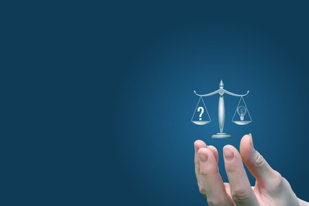A hand gently holds a scale symbolizing justice, with a question mark on one side and a light bulb on the other. This artwork suggests the balance between seeking answers and fairness.の写真素材