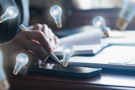 A person is engaged in a thoughtful brainstorming session at a desk, using a smartphone and taking...