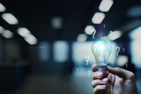 A person holds a light bulb in a dimly lit modern office, surrounded by floating question marks....