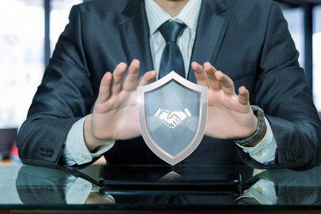 Businessman protecting digital security symbol during meeting. Professional man safeguarding a digital shield symbol representing security in a corporate setting.の写真素材