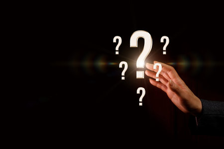 Hand of questions. A hand reaches for glowing question marks in a dark space, evoking curiosity and wonder.の写真素材