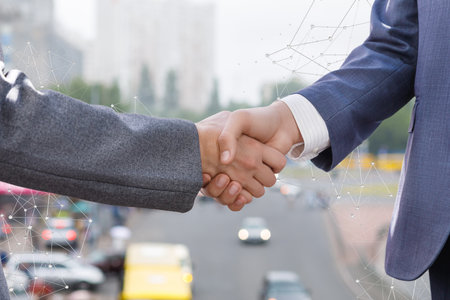 Dealers shake in the city. Two professionals shake hands warmly while surrounded by a bustling urban scene.の写真素材