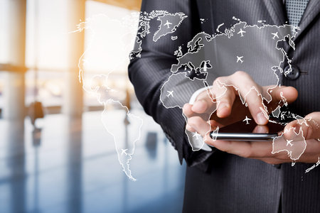 Global connection navigation. A businessman uses a smartphone while surrounded by a modern office space.の写真素材