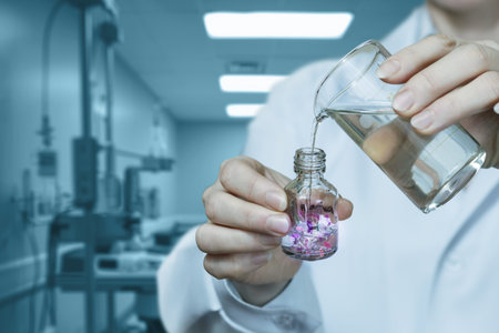 A scientist carefully pours liquid into a vial filled with colorful crystals.