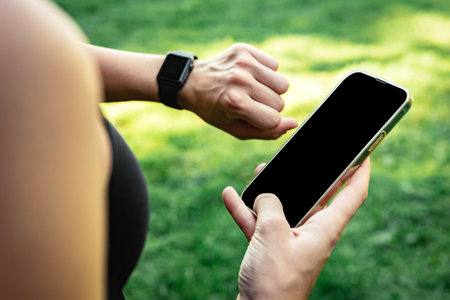Close up of athlete holds a mobile phone in his hands and tracks the results of training on a...