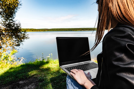 A young freelance woman working outdoors with laptop sitting in nature. Concept of freelancer...