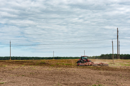 A tractor prepares the land using a seeder cultivator in autumn time.の写真素材