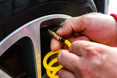 Man's hands inflating car wheel using automobile compressor with manometer.の写真素材