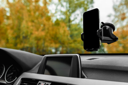 Car holder with mobile phone with black screen on windshield of car.の写真素材