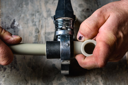 Plumber welding plastic pipes using welder machine.