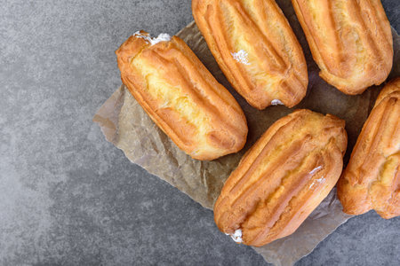 French eclairs filled with vanilla cream on gray background.