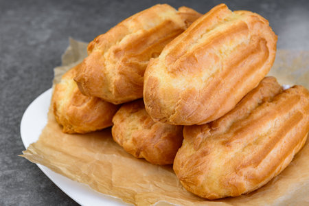 French eclairs filled with vanilla cream on gray background.