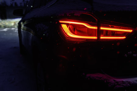 Night driving in winter. Close-up of rear light of car in winter in dark.