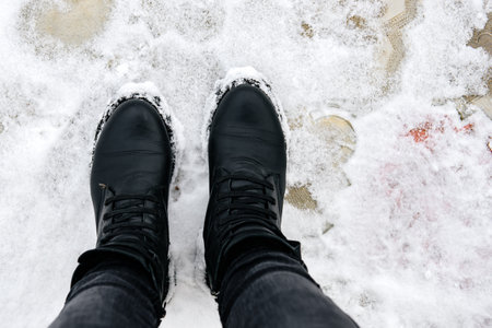 Woman in black winter leather boots on snow.の写真素材