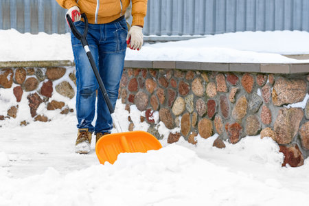 Cleaning snow from sidewalk and using snow shovel.の写真素材