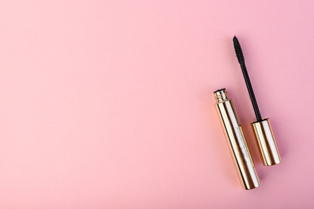 Black mascara in golden tube on pink background.の写真素材