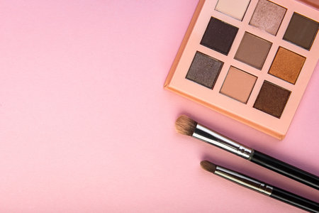 Eye shadow palette and makeup brushes on pink background.の写真素材