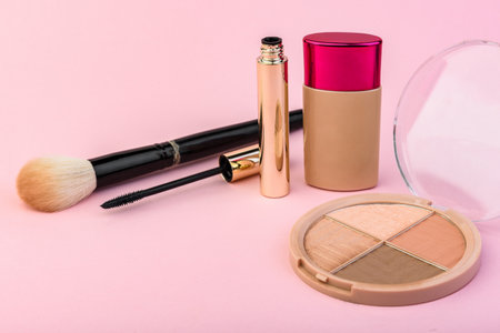 Makeup cosmetic products on pink background.