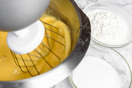 Beating eggs with an electric mixer for sponge cake dough.