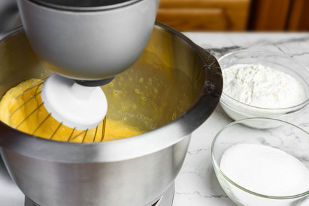 Beating eggs with an electric mixer for sponge cake dough.