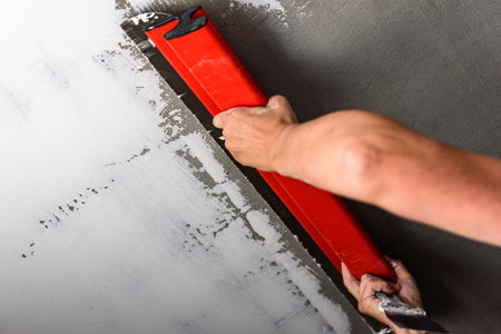 Woman plastering ceiling with finishing putty with putty knife or spatula.の写真素材