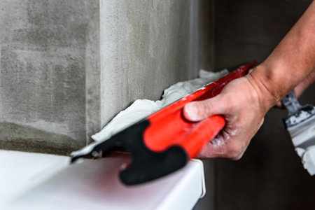 Woman plastering the walls with finishing putty in the room with putty knife or spatula.の写真素材