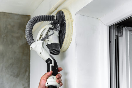 Painter polishing and sanding wall surface after putty for painting in new apartment.の写真素材