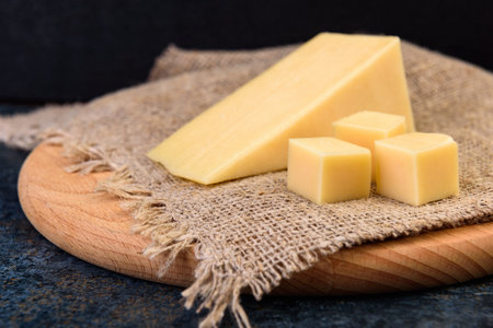Cheese on wooden board on dark background.の写真素材