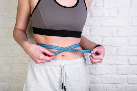 Sport and diet concept - trained belly with measuring tape.